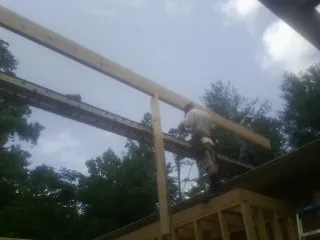 Carpenter setting a ridge beam over a new addition frame — Ice Dam Removal by Roofing Brothers in Wapello