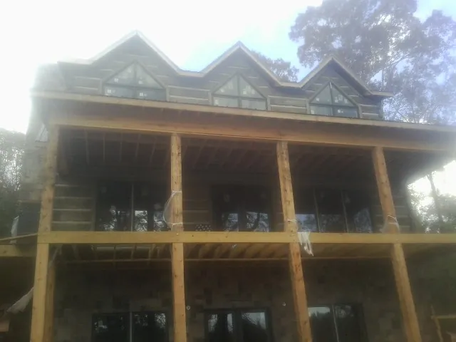 Dormers and porch framing on a large log home under construction — Roof Coating work by our crew in Wapello