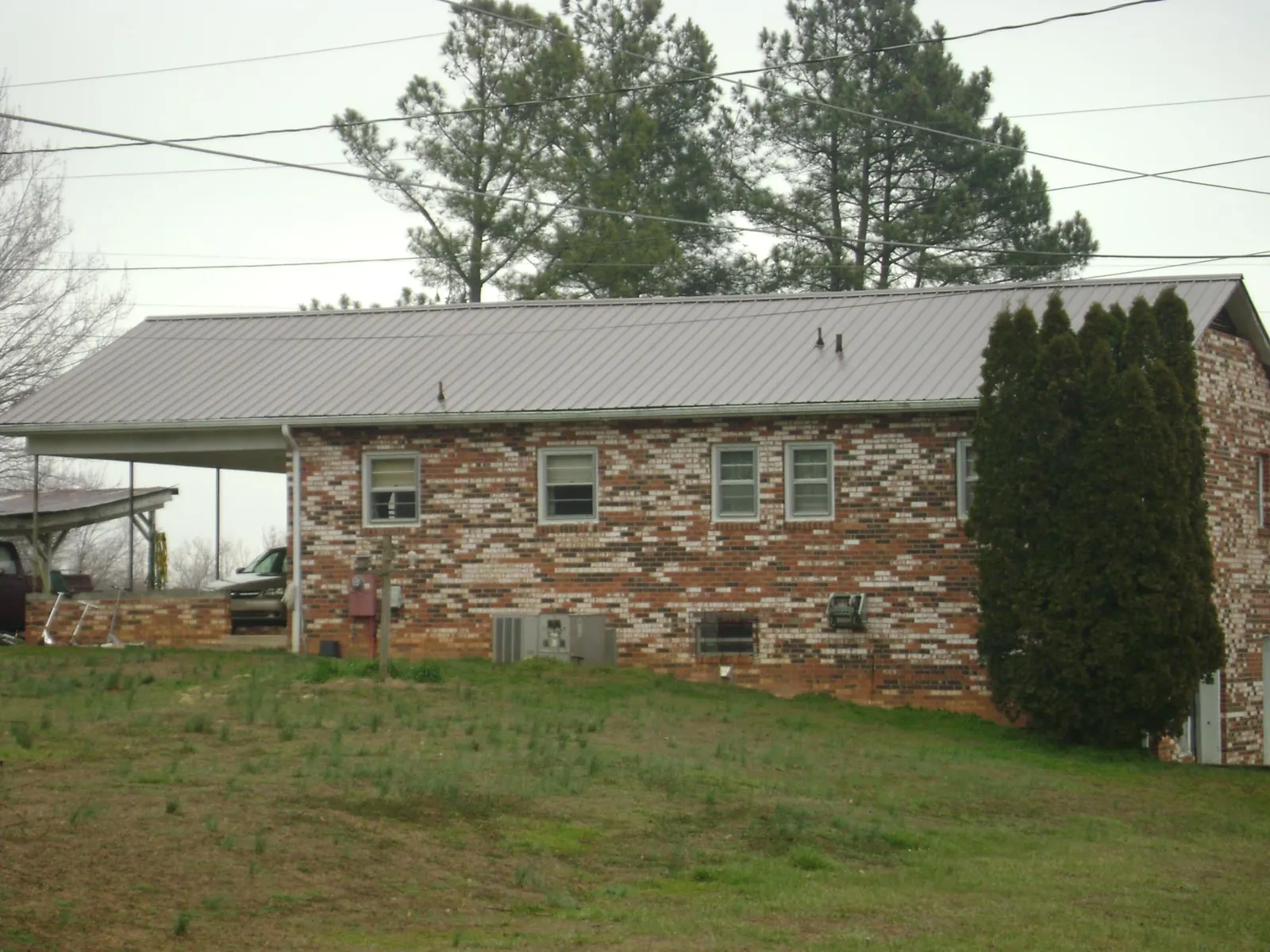 Gray metal roof on a brick split level home with a carport in Wapello