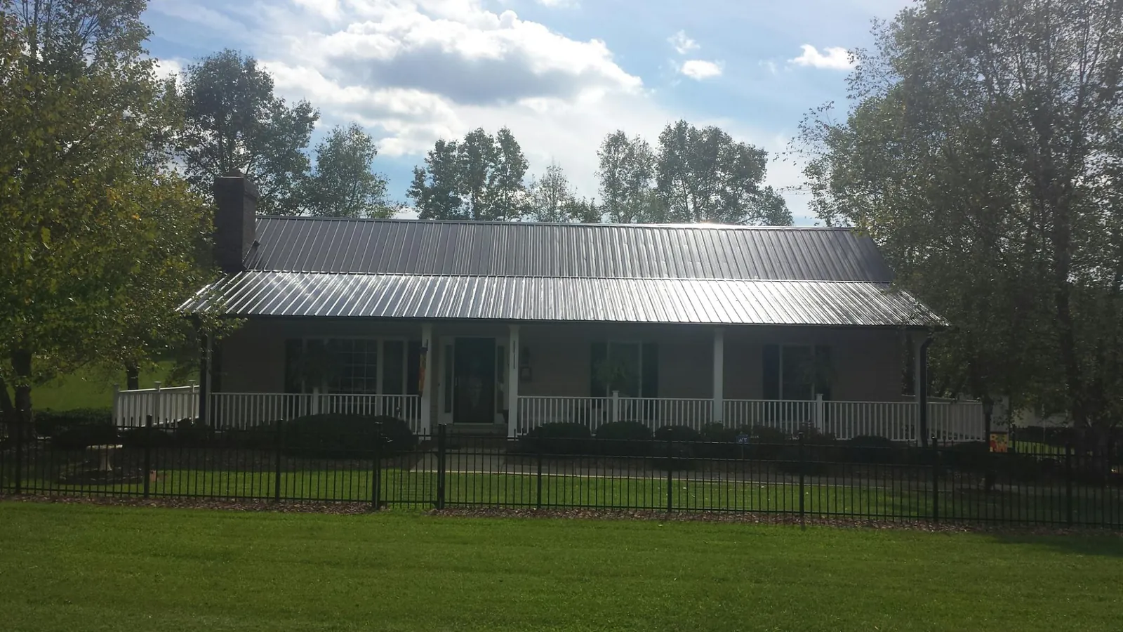Gray metal roof on a brick ranch with a full width front porch — Gutter Guard Installation work by our crew in Wapello