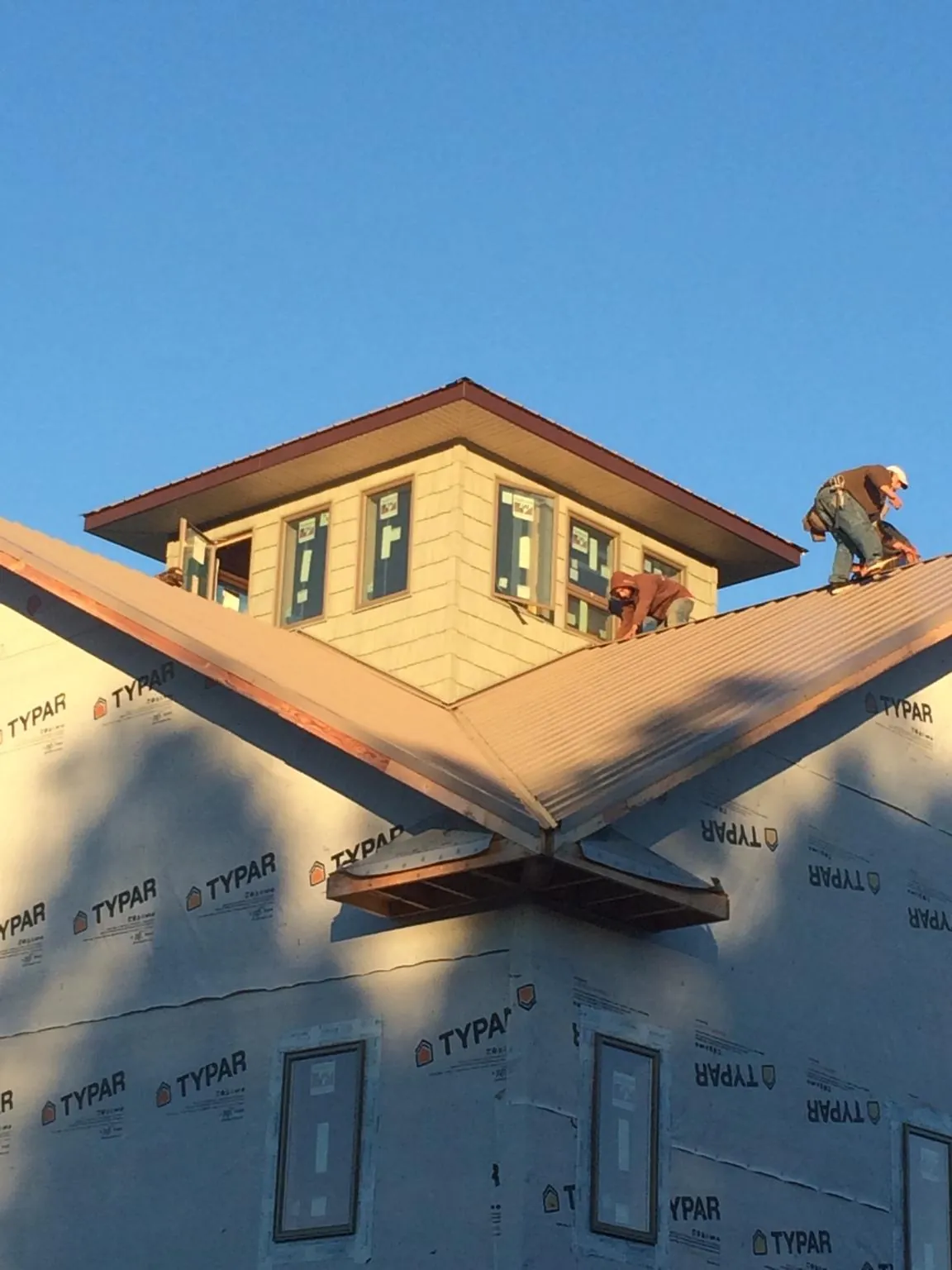 Roofers working around a rooftop cupola on a new metal roof at sunset — Roof Waterproofing in Wapello by Roofing Brothers